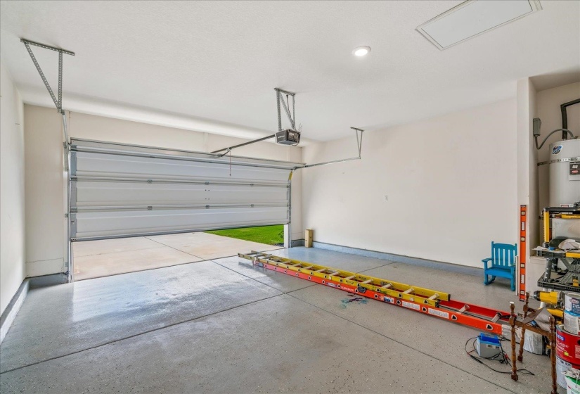 Spacious garage featuring a light gray epoxy floor coating, white walls, and an overhead door