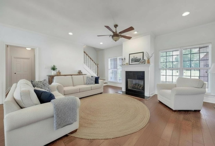 Living space featuring wood-finish flooring and a central fireplace with a white mantel and black hearth