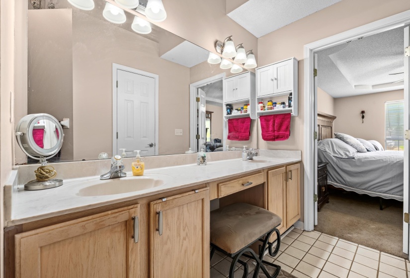 Double vanity featuring light wood-finish cabinetry, integrated sinks, and white countertops