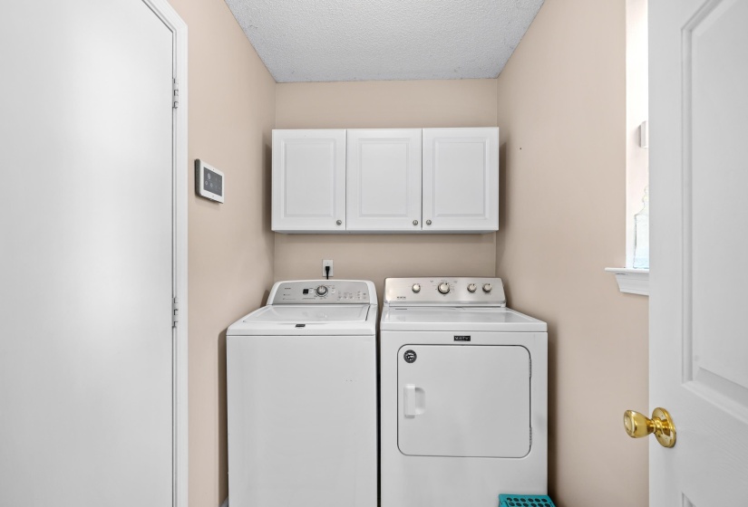Dedicated laundry area featuring overhead white cabinetry and a window