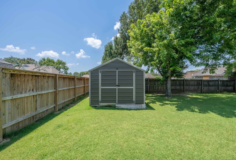 Expansive backyard featuring a well-maintained lawn and a metal storage shed on a concrete foundation