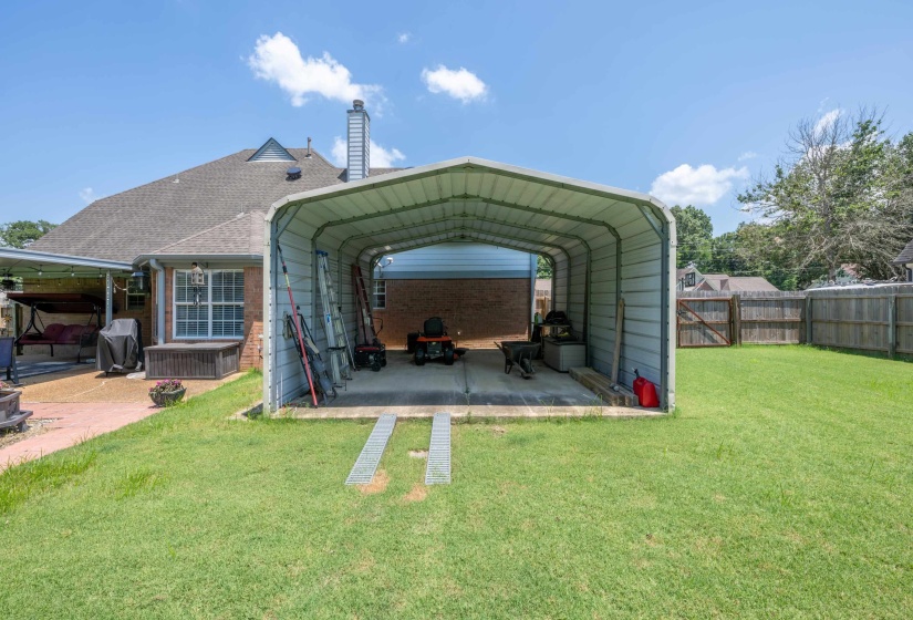 Rear exterior featuring a metal carport and a spacious grass lawn
