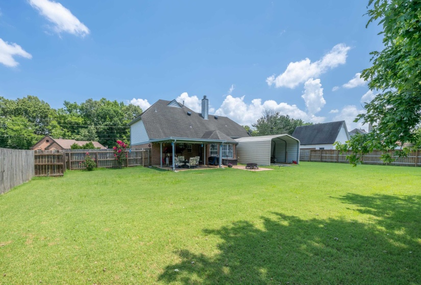 Expansive backyard featuring a manicured lawn, full privacy fencing, and mature perimeter trees
