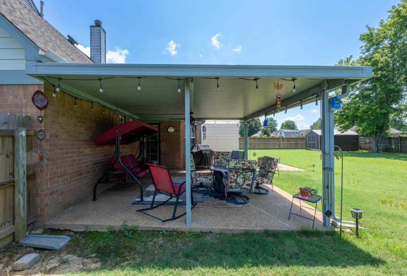 Expansive covered patio featuring a concrete slab, string lighting, and brick exterior