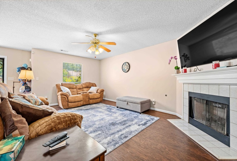 Living area featuring wood-finish flooring, a ceiling fan with integrated lighting, and a window with outdoor scenery