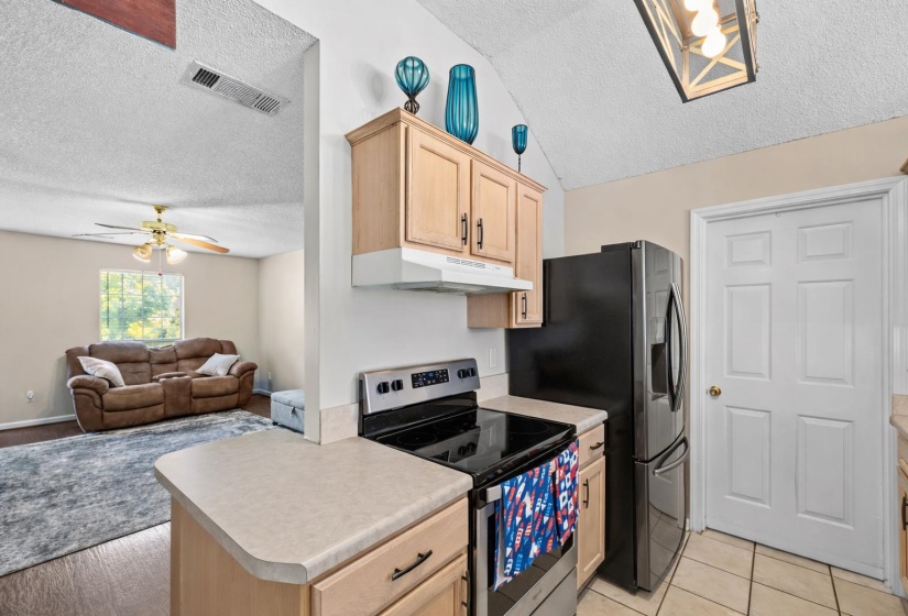 Kitchen area with light wood-finish cabinetry, light countertops, and tile flooring