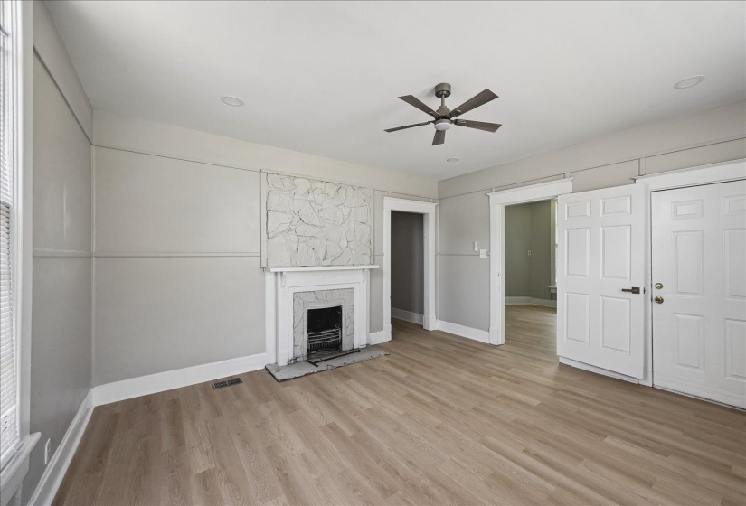 Spacious room featuring wood-finish flooring, a decorative fireplace with a mantel, and panel molding