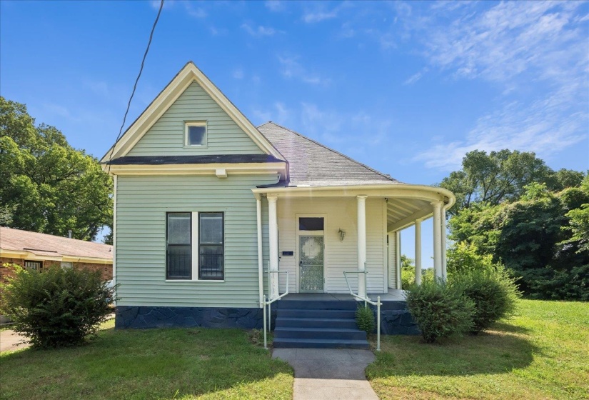 Classic American Foursquare architecture featuring light green siding and a contrasting dark blue foundation