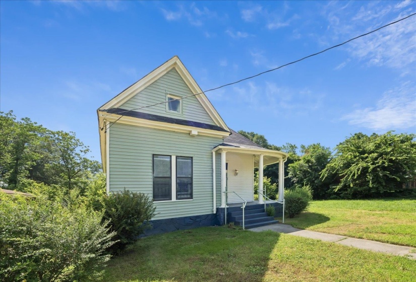 Light green siding exterior with a traditional gable roof and dark trim accents