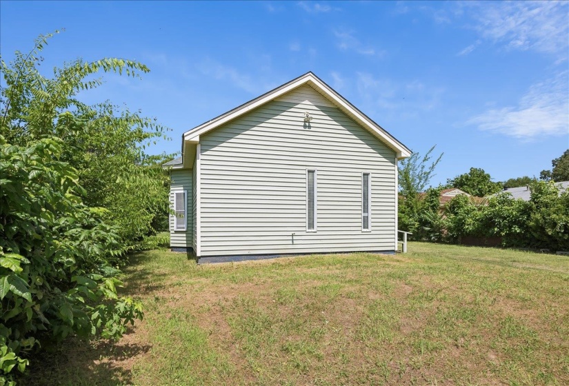 Light green siding exterior with a dark foundation, featuring two tall vertical windows