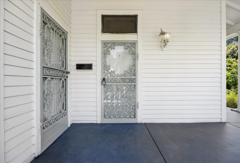 Front porch featuring white horizontal siding, a blue-painted concrete floor, and an ornate security screen door