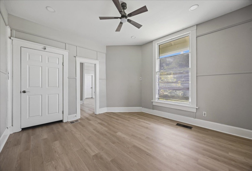 Spacious room featuring wood-finish flooring, a ceiling fan, recessed lighting, and a large window with white trim