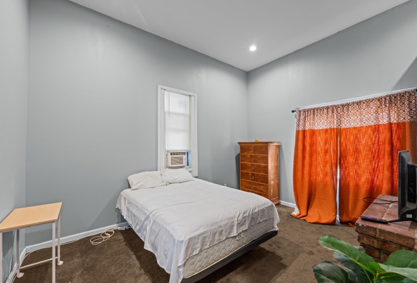Carpeted room featuring light gray walls, a single window with a window-mounted unit, and a recessed ceiling light