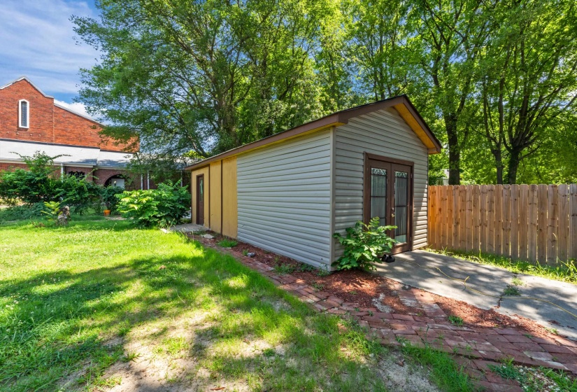 Detached shed with light gray siding and brown trim