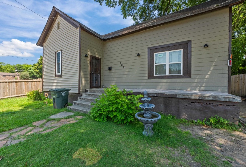 Exterior featuring horizontal siding, a fenced yard, a tiered concrete fountain, a concrete front porch, and concrete steps