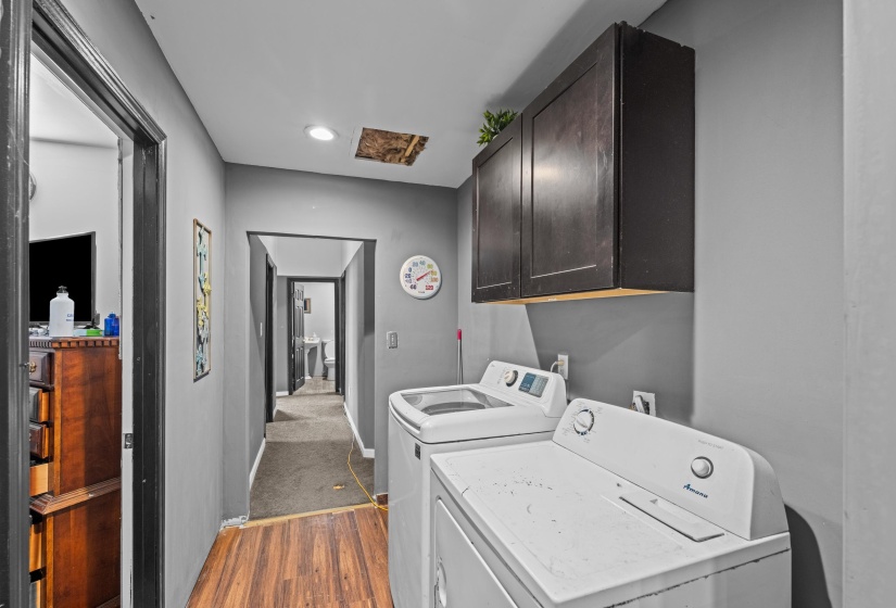 Dedicated laundry area featuring wood-finish flooring and dark wood-tone cabinetry