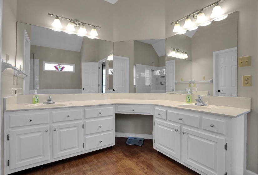 Full bathroom with double vanity, dark wood-style floors, a walk in shower, and lofted ceiling