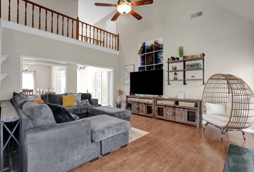 Living area with ceiling fan, wood finished floors, a high ceiling, and suspended lighting