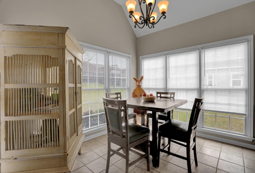 Dining room with lofted ceiling, light tile patterned floors, and suspended lighting