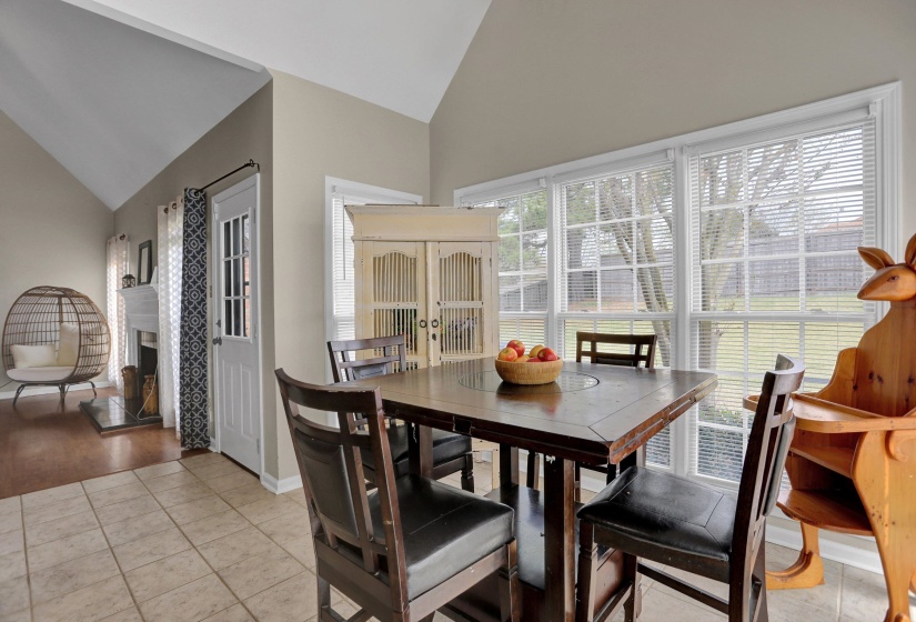 Dining room with vaulted ceiling, a fireplace with raised hearth, and light tile patterned floors