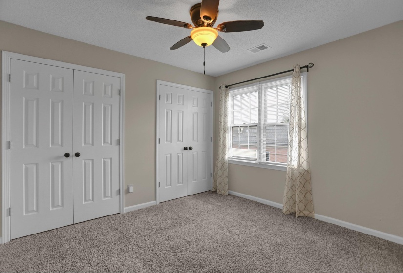 Unfurnished bedroom with multiple closets, carpet flooring, ceiling fan, and a textured ceiling