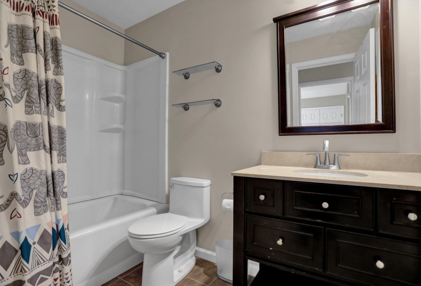 Full bath featuring vanity, shower / bath combo, and dark tile patterned floors