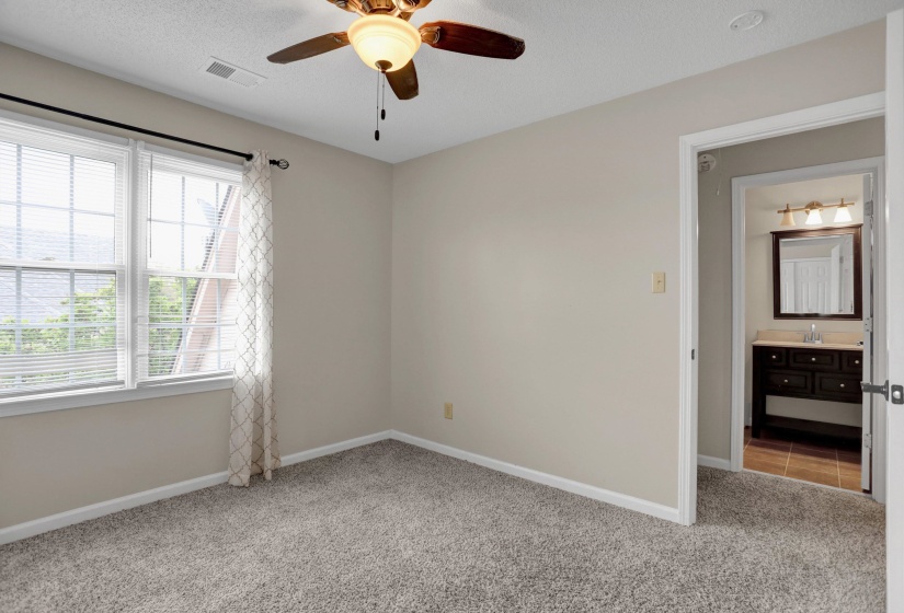 Empty room featuring ceiling fan, light carpet, and a textured ceiling