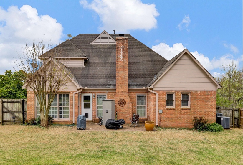 Back of property featuring brick siding, a fenced backyard, a gate, and a chimney