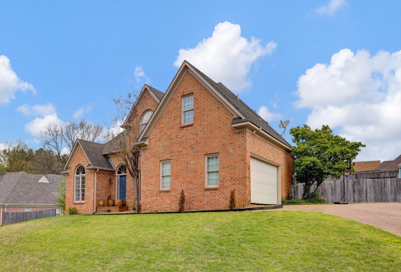 View of front facade featuring brick siding, driveway, and a garage