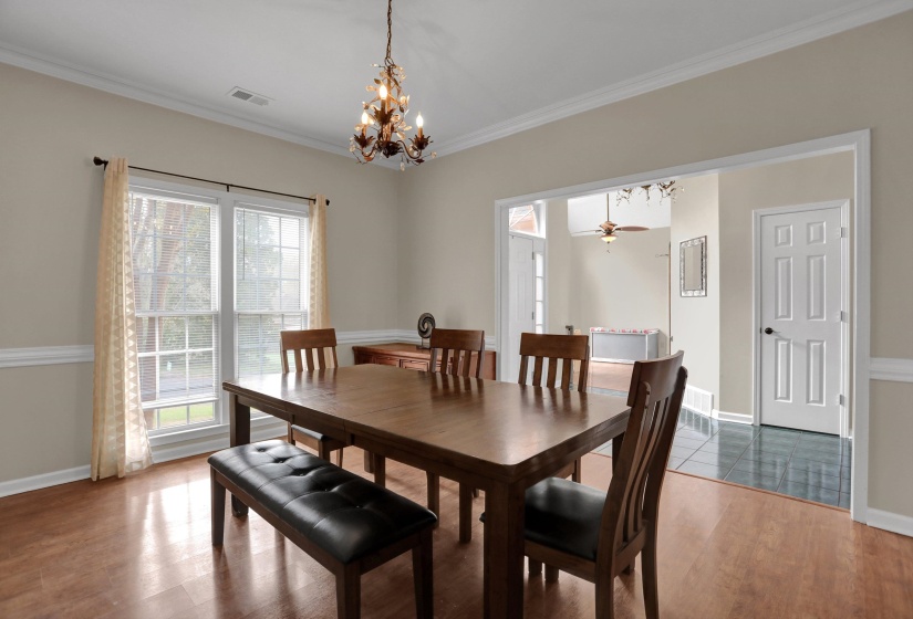 Dining room featuring a chandelier, crown molding, wood finished floors, and a ceiling fan
