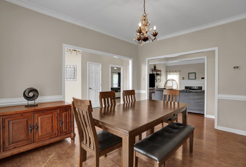 Dining area with ornamental molding, a chandelier, wood finished floors, and a fireplace