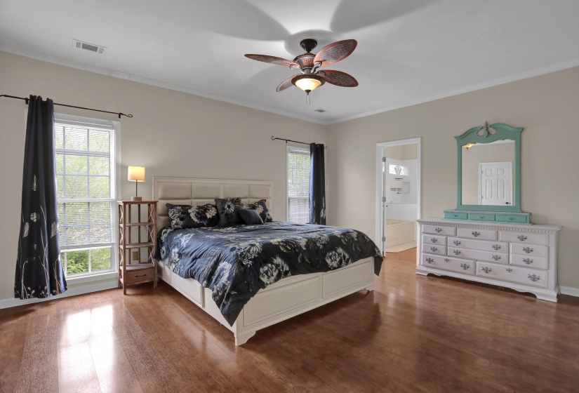 Bedroom with wood finished floors, crown molding, a ceiling fan, and ensuite bathroom