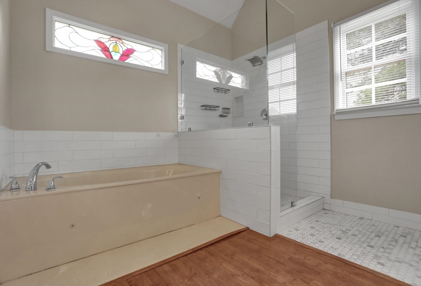 Bathroom featuring a walk in shower, a garden tub, and light wood-style floors