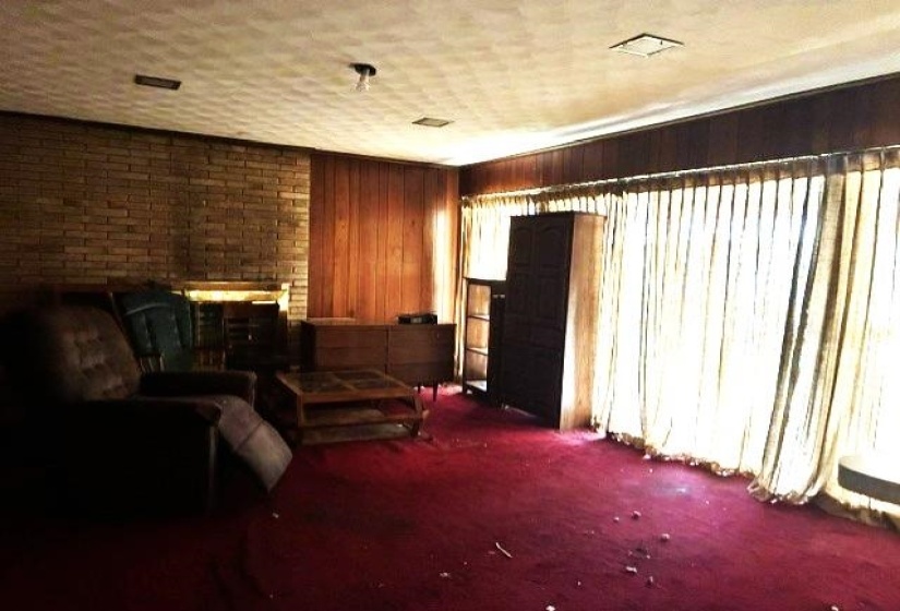 Room featuring a brick accent wall, wood paneling, and wall-to-wall carpeting