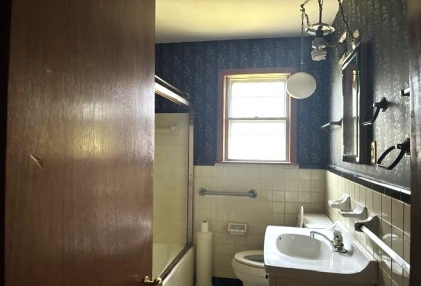 Bathroom featuring a window, vanity with integrated sink, wall-mounted mirror, and a tub with a shower enclosure