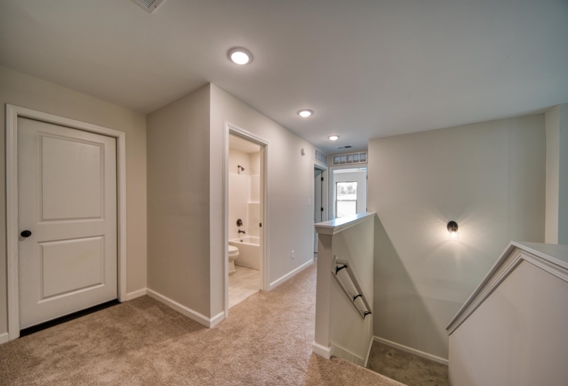 Hall featuring an upstairs landing, light colored carpet, and recessed lighting