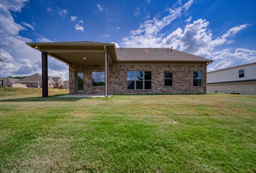 Back of house featuring a patio, a lawn, brick siding, and a shingled roof