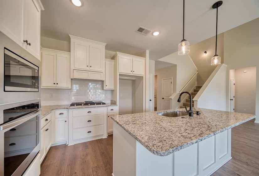Kitchen with appliances with stainless steel finishes, backsplash, light stone counters, light wood finished floors, and recessed lighting