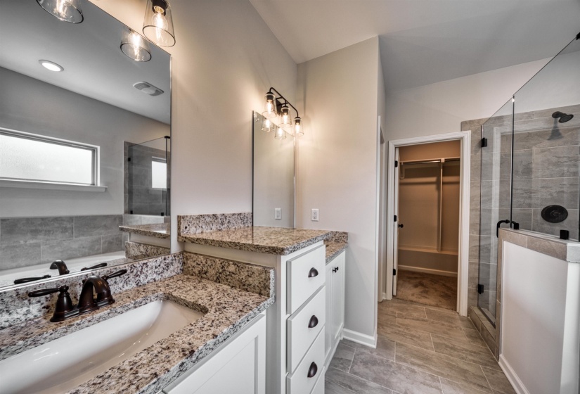Bathroom with a spacious closet, vanity, a shower stall, and a garden tub
