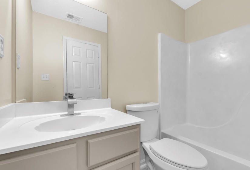 Bathroom featuring a white vanity with an integrated sink, brushed nickel faucet, and a large wall-mounted mirror