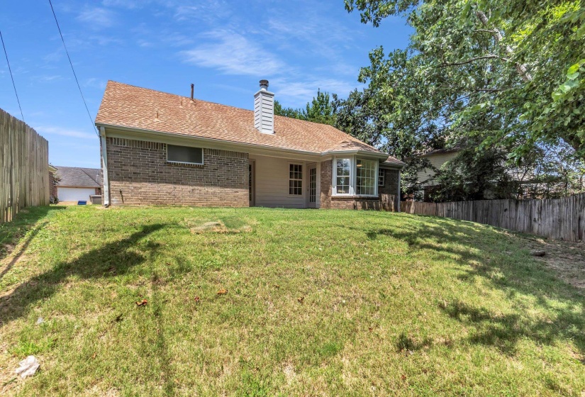 Expansive sloped backyard featuring mature trees