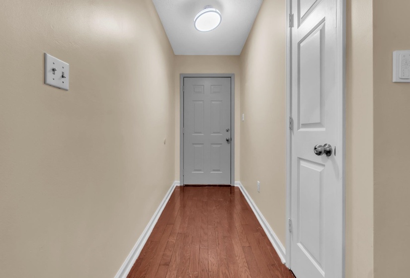 Hallway featuring wood-finish flooring, light beige wall paint, white trim, and a ceiling-mounted light fixture