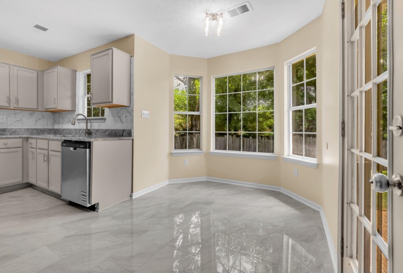 Kitchen with light cabinetry, stainless steel dishwasher, and stone-look countertops