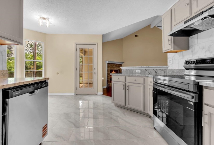 Kitchen featuring light-toned cabinetry, stainless steel appliances, and marble-look tile flooring