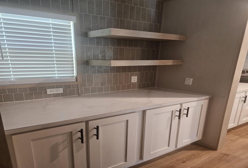 Built-in coffee bar with flat-panel doors and black hardware, complemented by light-toned countertops