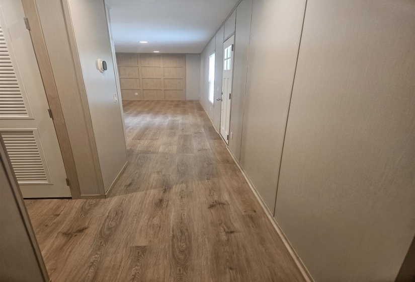Hallway featuring wood-finish flooring, recessed lighting, and a paneled accent wall