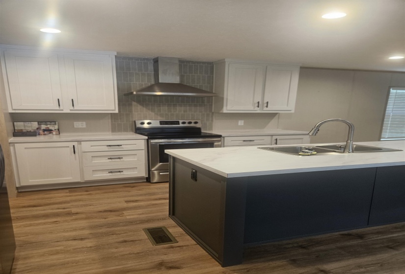 Contemporary kitchen featuring a dark-toned island with an undermount sink and gooseneck faucet
