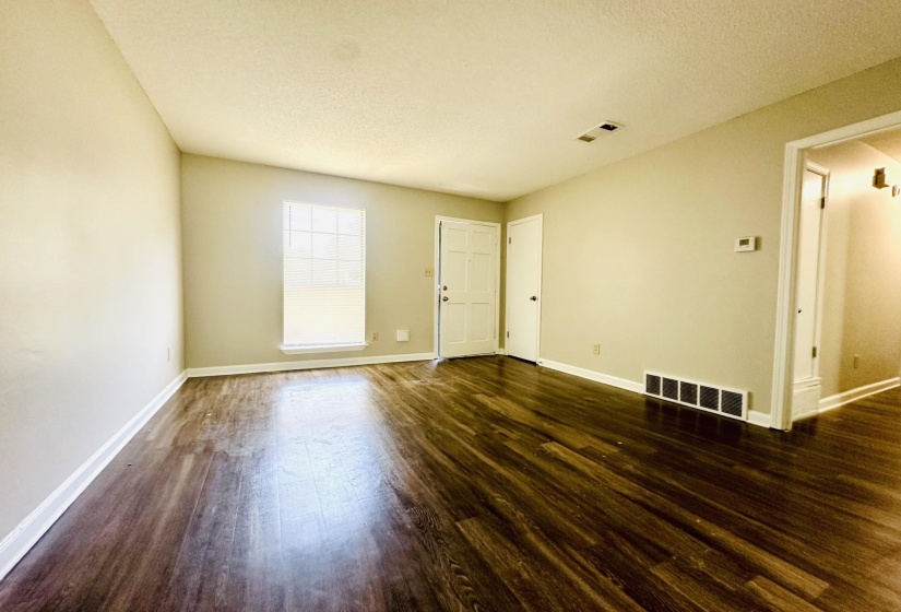 Spacious interior featuring dark wood-finish flooring, light neutral-toned walls, and white baseboards
