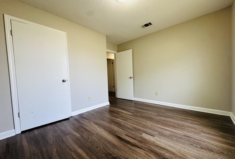 Room featuring dark wood-finish flooring, light-toned walls, and white trim