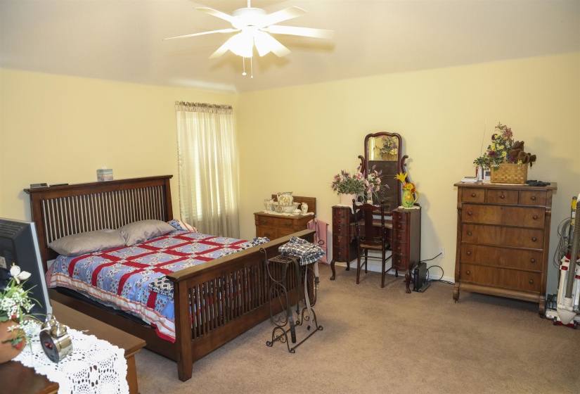 Spacious room featuring carpeting, light-toned walls, and a ceiling fan with light fixture